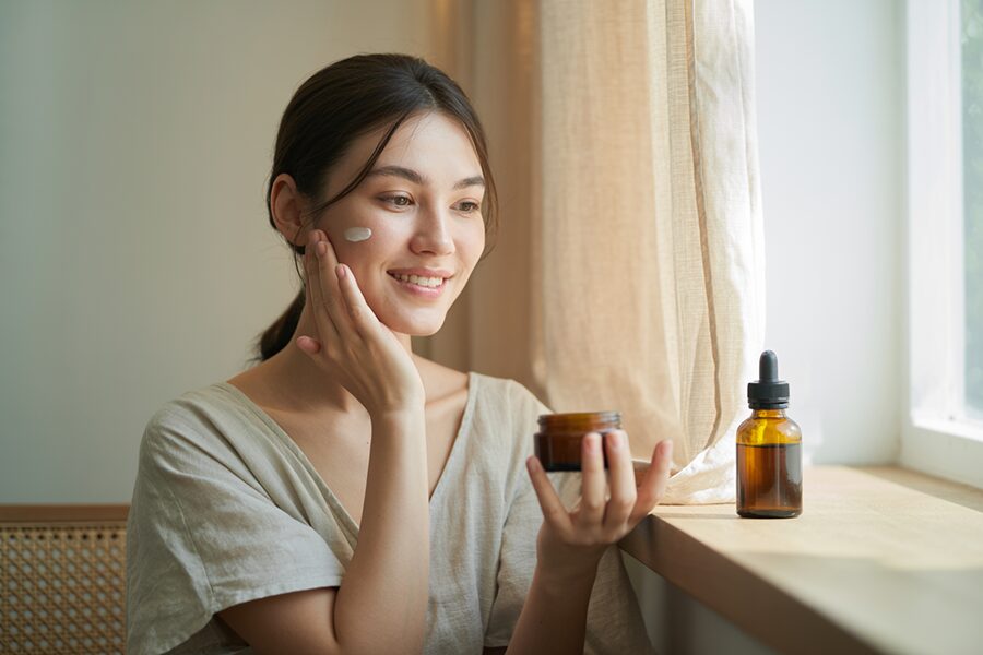 Người phụ nữ chạm nhẹ làn da sau khi dùng kem dưỡng dầu hạt trà