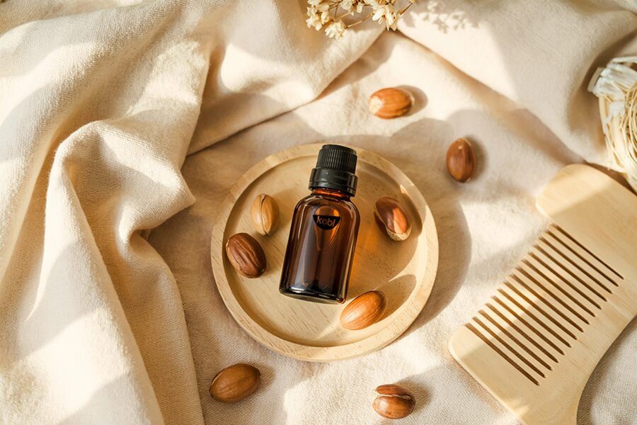 Chai dầu argan bên cạnh khăn vải, lược gỗ và hạt argan khô