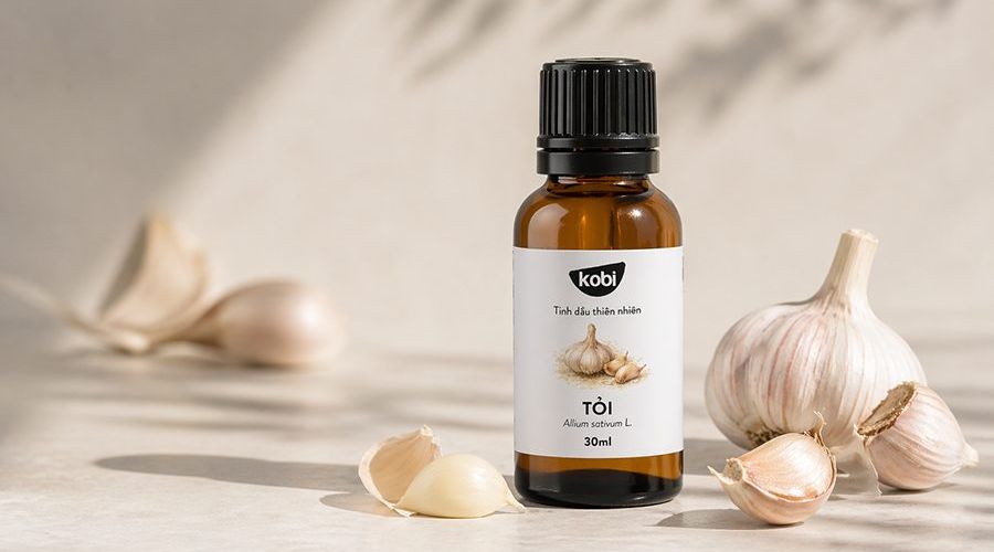 Tinh dầu tỏi trong bố cục tổng quan với củ tỏi tươi và chai thủy tinh nâu